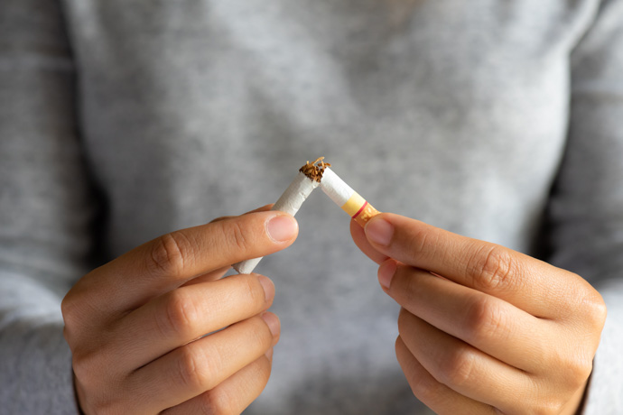 Persona que rompe un cigarrillo para no padecer los efectos del tabaco en la piel.