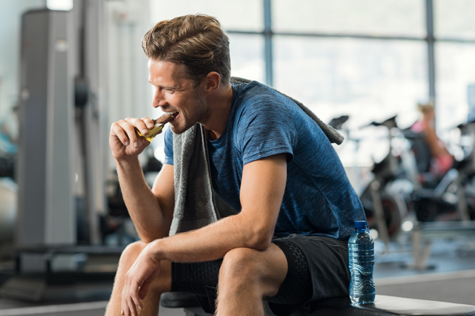 Hombre en el gimnasio comiendo una barra de chocolate