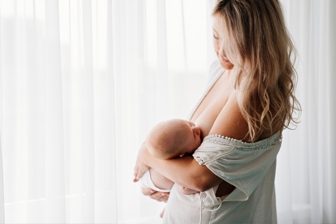 Mamá amamantando a su bebé cerca de ventana