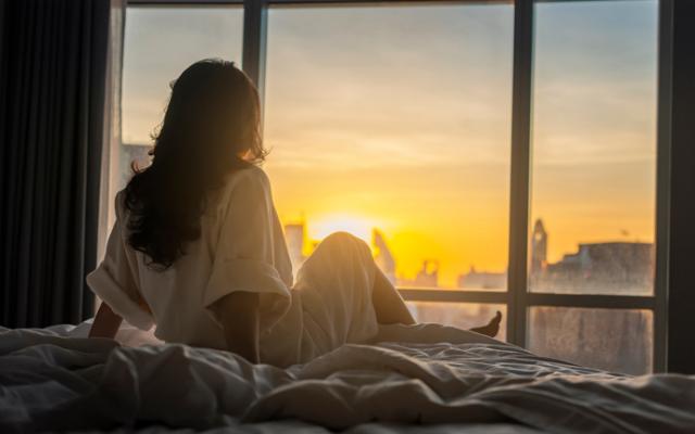 Mujer despertándose con la luz del sol desde su ventana