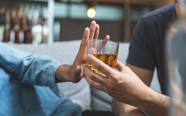 Hombre que sabe cuánto tarda el cuerpo en eliminar el alcohol rechazando una copa.