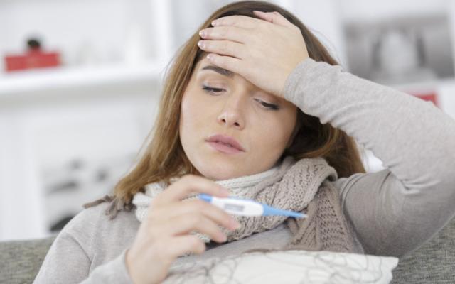Mujer usa termómetro para saber si tiene fiebre