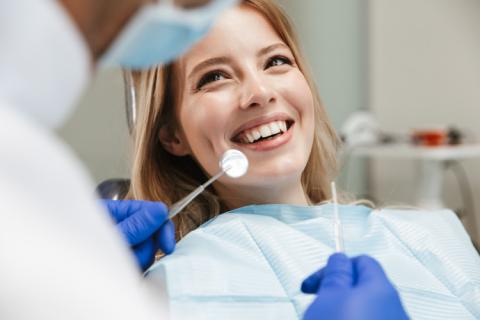 Dentista revisando si una mujer toma vitaminas para fortalecer sus dientes.