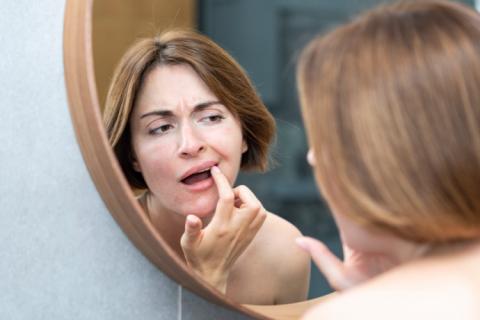 Mujer examinando en el espejo sus manchas marrones en los dientes. 